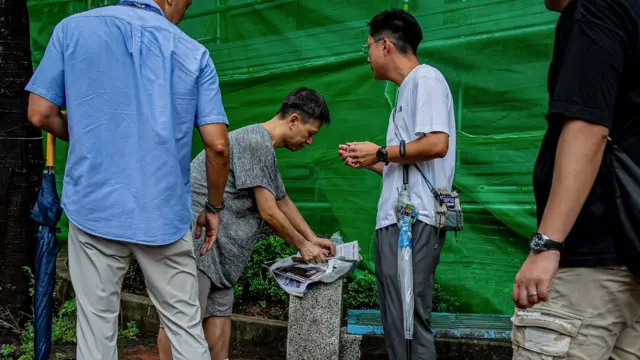 香港西九龙裁判法院外便衣警员搜查邓岳君(中间灰白色上衣者)的随身物品(21/8/2026)