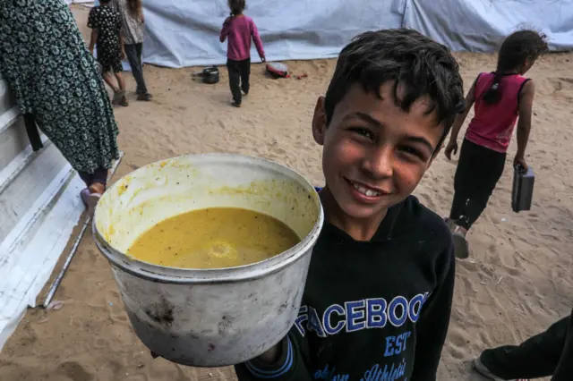 طفل فلسطيني سعيد بتلقي وجبة ساخنة من مطبخ خيري في خان يونس