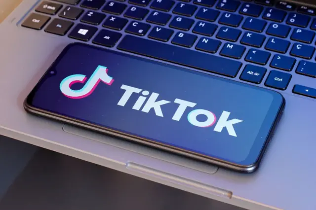 dizüstü bilgisayar üzerindeki bir telefonda Tiktok logosu 