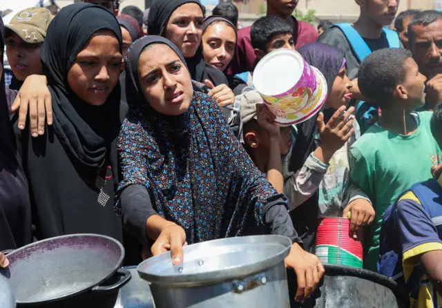فلسطينيون متجمعون أمام مطبخ خيري للحصول على الطعام وسط قطاع غزة.