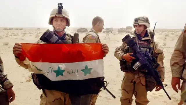 Wanajeshi wa Marekani wakiwa na bendera ya Iraq iliyokamatwa.
