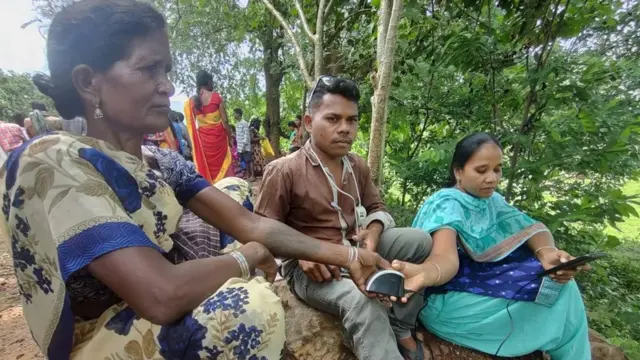 బయోమెట్రిక్ వేలిముద్ర వేస్తున్న గిరిజన మహిళ