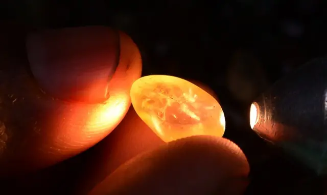 In this photograph taken on February 17, 2016, a Sri Lankan gem dealer uses a torch to examine precious stones for flaws in Ratnapura district, some 100 kilometres southeast of Colombo. From the Queen of Sheba to Britain's Duchess of Cambridge, Sri Lanka's sapphires have adorned royalty through the ages, but a flood of cheap imitations is threatening the island's reputation for the precious stones. / AFP / LAKRUWAN WANNIARACHCHI / TO GO WITH AFP STORY SRILANKA-LUXURY-MINING-SAPPHIRE,FEATURE BY AMAL JAYASINGHE (Photo credit should read LAKRUWAN WANNIARACHCHI/AFP via Getty Images)