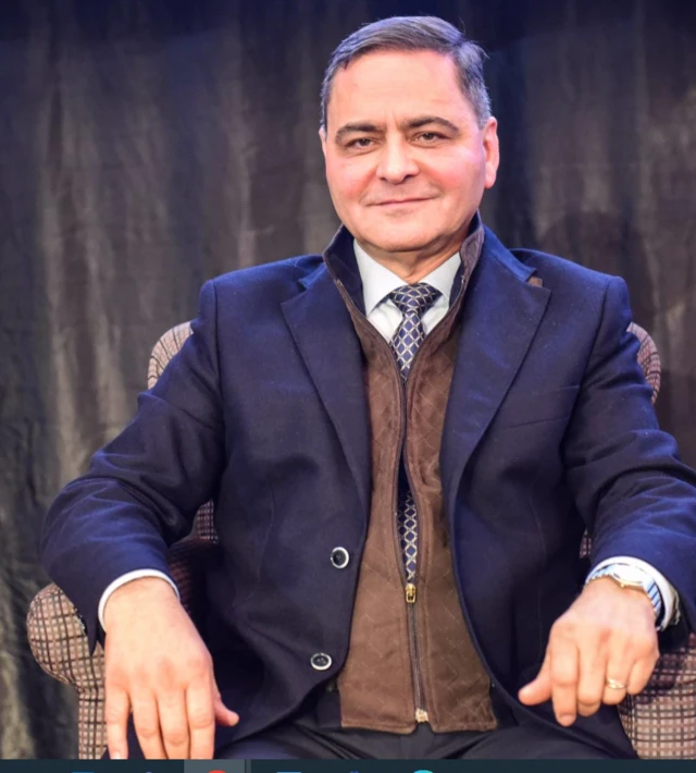 رجل الأعمال الفلسطيني، سمير حليلة يجلس على مقعد ويرتدي سترة زرقاء وقميضاًًَ أبيض وربطة عنق.