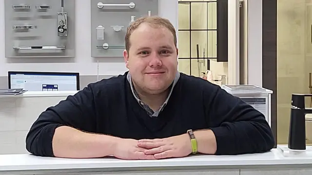 Чоловік зі світлим волоссям спирається на прилавок руками та руками
