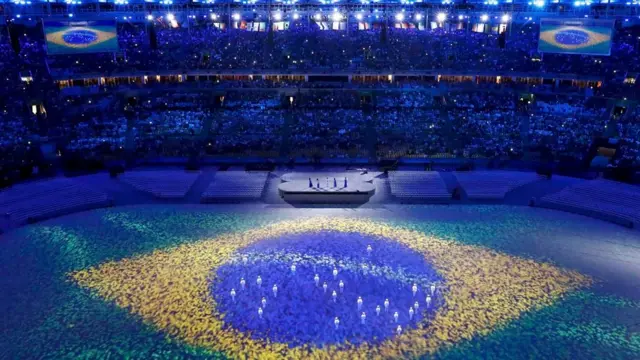 luzes que traziam nas roupas depois formaram as estrelas da bandeira brasileira projetada no estádio.