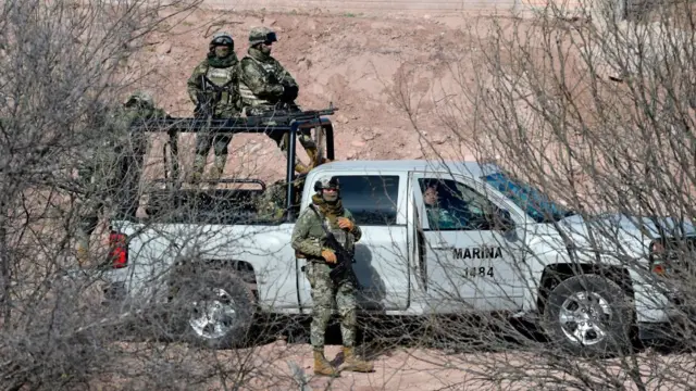 Militares mexicanos en una furgoneta blanca en medio de un campo