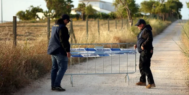 Arama yapılan alana polis tarafından bir bariyer yerleştiriliyor. İki polis demir bariyeri taşıyor