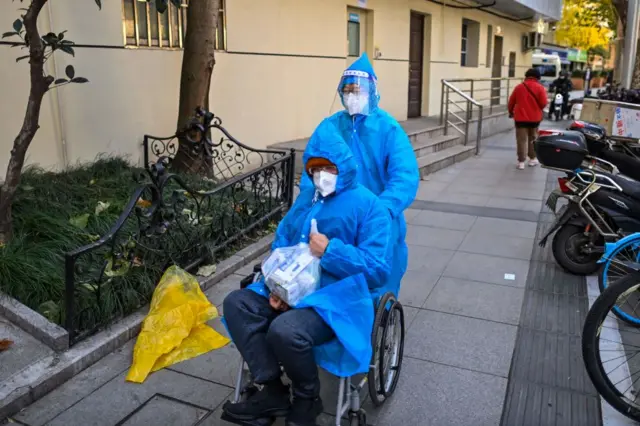 Dua orang mengenakan pakaian pelindung terlihat di samping klinik di Rumah Sakit Huadong di Shanghai, China, Senin (19/12).