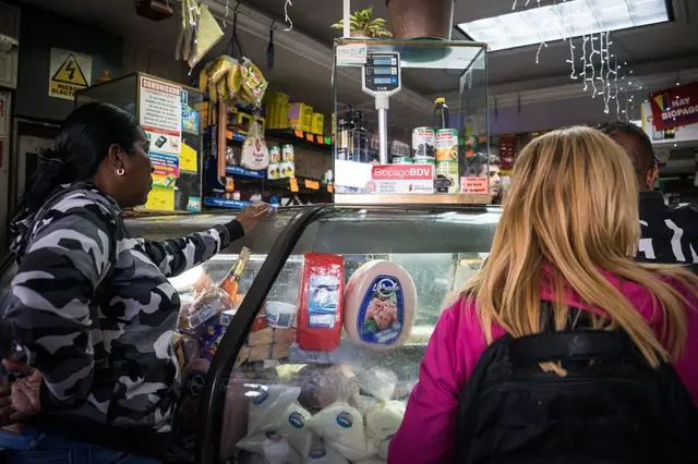 Mulheres em balcão de comércio de alimentos em Caracas