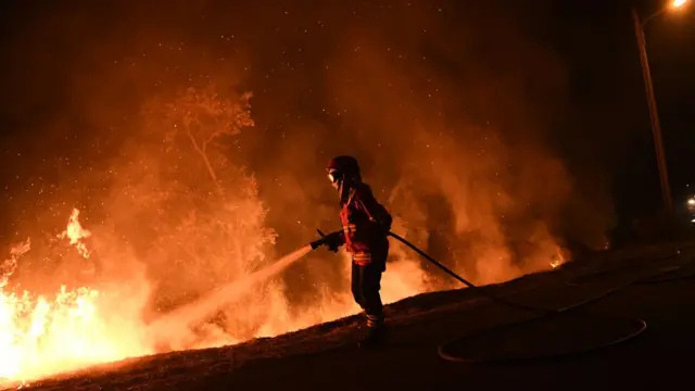 A firefighter tries to extinguish a fire in Cabanoes near Louzan as wildfires continue to rage in Portugal on October 16, 2017