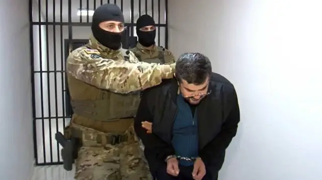 Лидера непризнанной НКР Араика Арутюняна ведут в наручниках двое в камуфляже и масках.