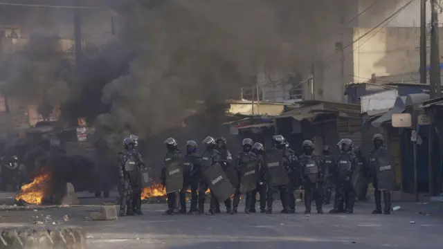 Gendarmes with smoke rising behind dem for Dakar, Senegal - 9 February 2024