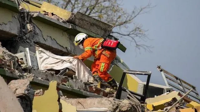 Seorang anggota tim penyelamat sedang mencari korban gempa Myanmar di atas reruntuhan bangunan.