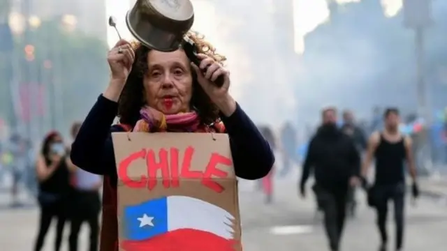 Mulher batendo panela durante protesto no Chile