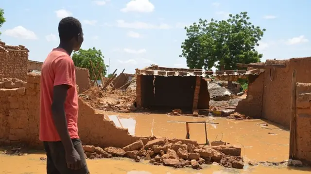 Wani mazaunin Kirkissoye a Yamai kenan yana tsaye yana kallon yadda ambaliyar ta lalata gidansu.