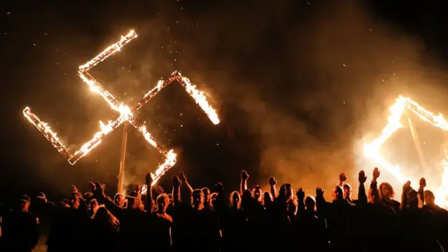 Simpatizantes del niazismo con una esvástica de fuego al fondo