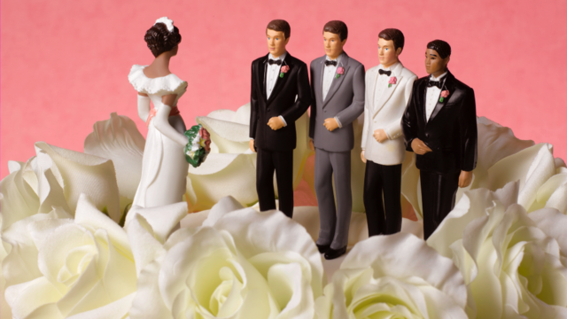 Un gâteau de mariage avec les figures d'une mariée et de trois mariés