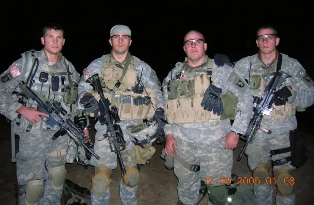 Ночное фото четырех американских военнослужащих, включая Пита Хегсета, в камуфляже и бронежилетах, стоящих плечом к плечу. Все в защитных очках, трое держат винтовки. Внизу кадра — цифровая метка даты: 12.09.2005 
