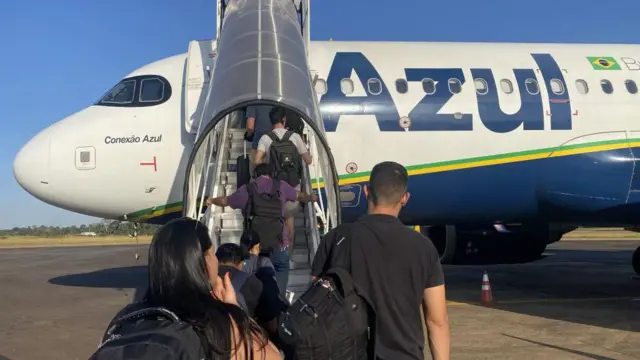 Passageiros embarcando em avião da companhia aérea Azul num dia de céu sem nuvens 