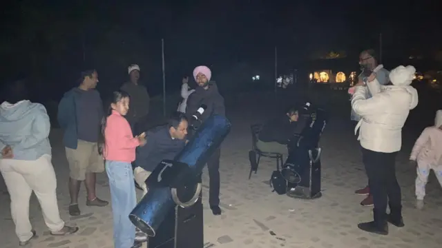 People gather around telescoped pointed towards the sky during an astronomy workshop near Sariska Tiger Reserve in Rajasthan, India