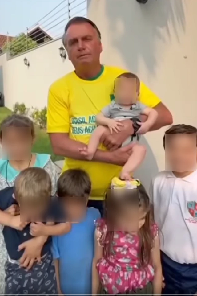 Bolsonaro rodeado de crianças e segurando um bebê