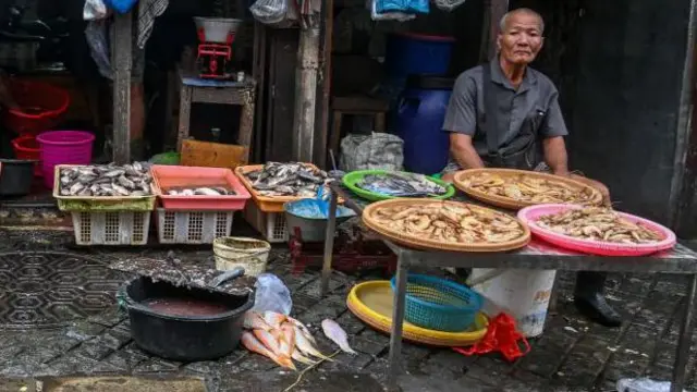 Seorang penjual ikan menunggu calon pembeli di sebuah pasar di Surabaya, Jawa Timur, pada Juli 2024.