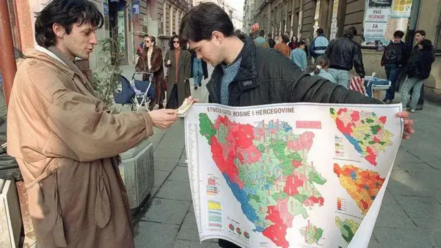 Торговець продає етнічну мапу Боснії та Герцеговини на вулиці Сараєва, 1 березня 1992 року. Червоним кольором позначені райони з перевагою сербів, зеленим - босняків-мусульман, синім - хорватів. До повномасштабної війни лишається кілька тижнів