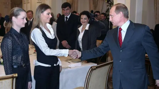 O presidente russo Vladimir Putin aperta a mão das famosas ginastas russas Alina Kabaeva e Svetlana Khorkina durante o encontro com esportistas, candidatos à equipe olímpica russa para as Olimpíadas de 2004, na residência presidencial em Novo-Ogaryovo, nos arredores de Moscou, em 10 de março de 2004.