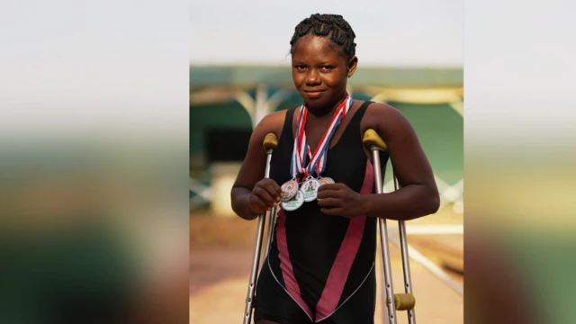 A girl hold medals while standing wit crutches