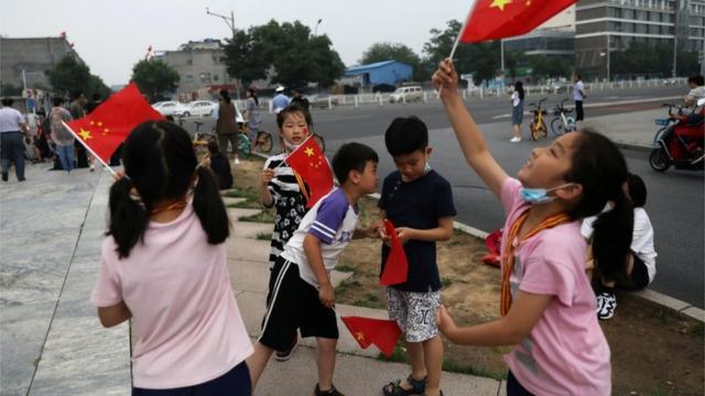 等待中共成立100週年慶祝典禮排練的兒童在揮舞五星紅旗。
