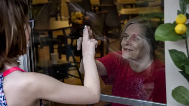 Abuela y nieta detrás de una ventana.