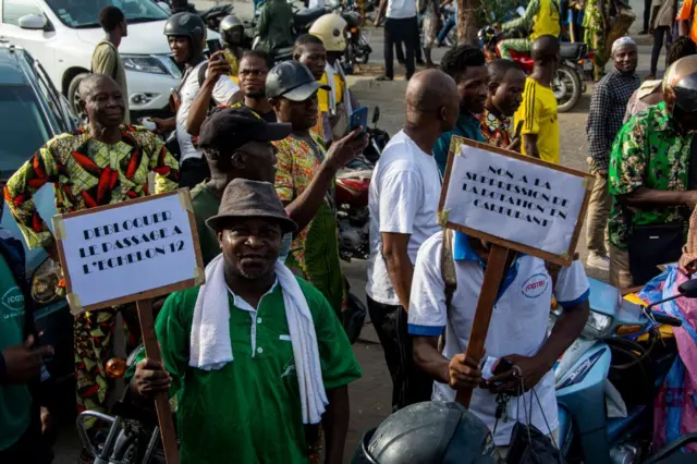 Des manifestants brandissent des pancartes lors d'une marche contre la cherté de la vie à Cotonou, le 27 avril 2024