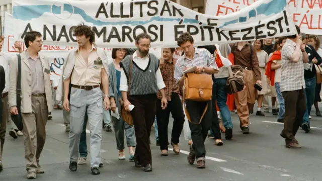 Nick Thorpe, a BBC budapesti tudósítója Vargha Jánossal, a Bős-Nagymarosi vízi erőmű ellen tiltakozó Duna Kör mozgalom alapítójával készít interjút egy tüntetésen.