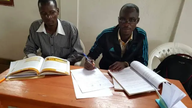 Umwigisha Hajayandi Léonce (i bubamfu) hamwe n'umuganga Izompa Manifred baje gusoma