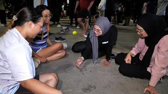 Empat orang perempuan sedang bermain bekel