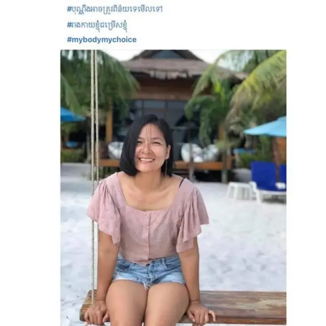 Cambodian woman sits on swing wearing shorts at the beach