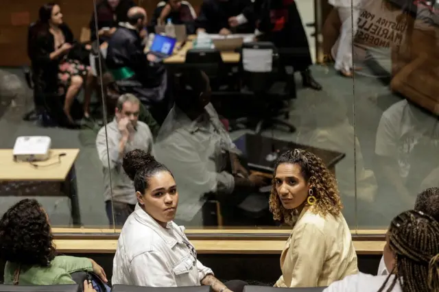 Luyara e Anielle sentadasbaixar casas das apostasplateia da sala do tribunal, olhando para trás com olhar sério