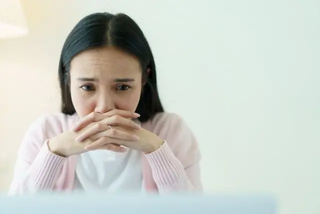 فتاة تضع وجهها على يديها ويبدو عليها التوتر والقلق