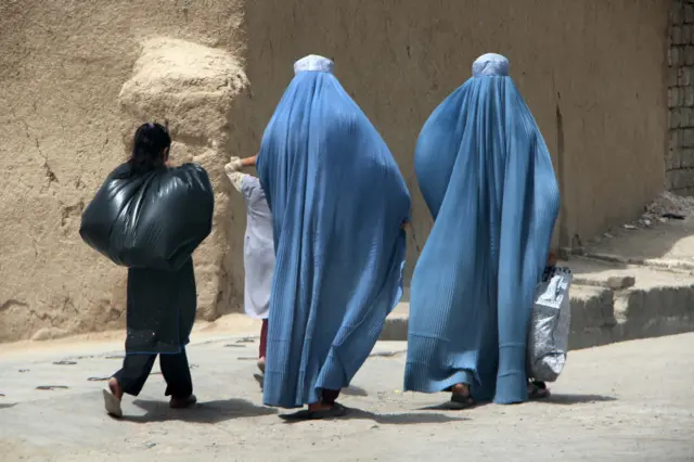 دو زن افغان که چادری به سر دارند و دو کودک در کنار آنهاست