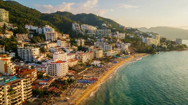 Praia de Puerto Vallarta, no México, com prédios e morros ao fundo