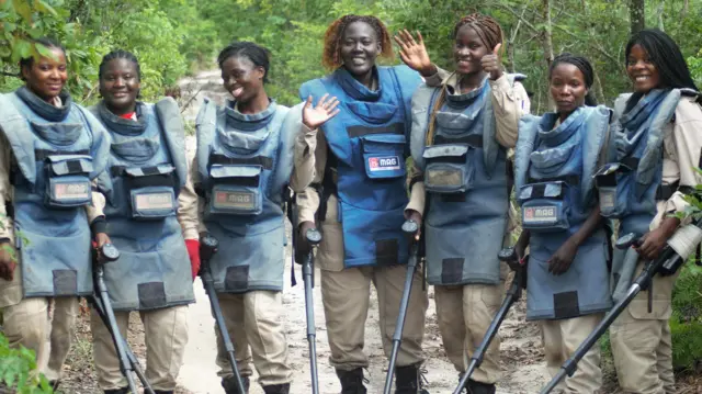 Une équipe de démineuses en Angola sourit et fait signe à la caméra.