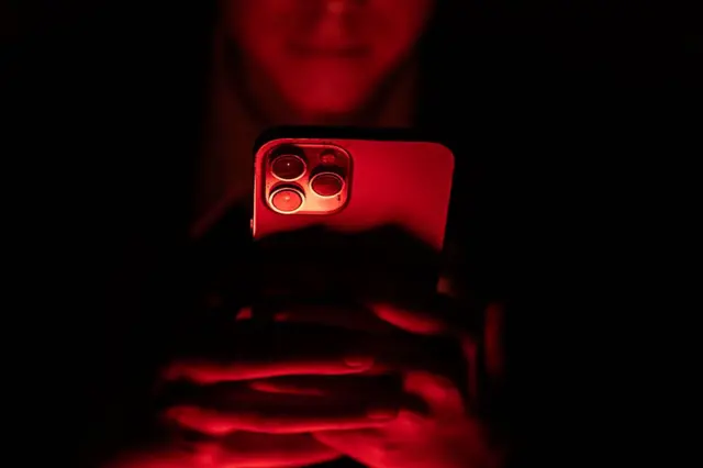 Jovem usando celular no escuro