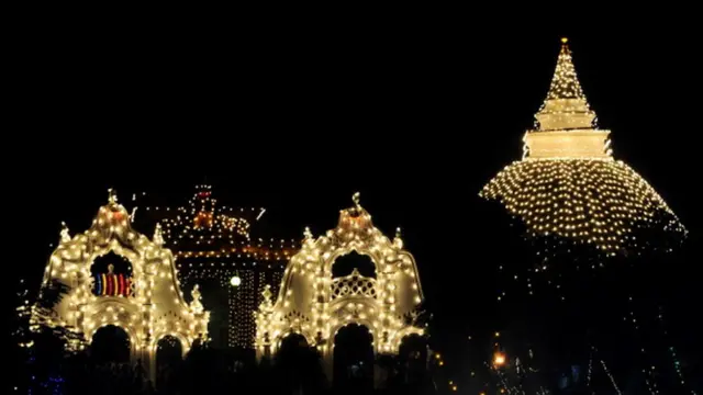 Sri Lankan Buddhist devotees gather around an illuminated temple in Kelaniya