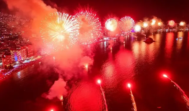 Fuegos artificiales verdes y anaranjados en la playa 