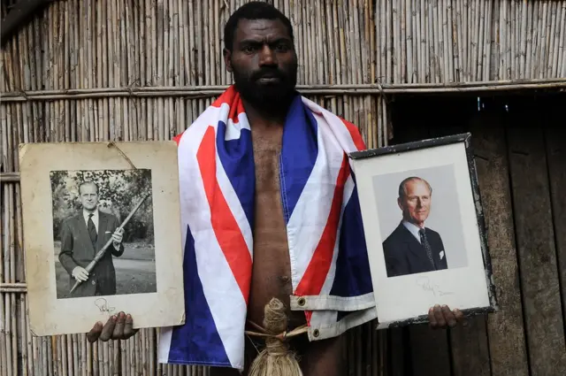 Sikor Natuan, membre de la tribu, tient deux portraits du prince Philip de Grande-Bretagne devant la hutte du chef du village isolé de Yaohnanen, sur l'île de Tanna, au Vanuatu.