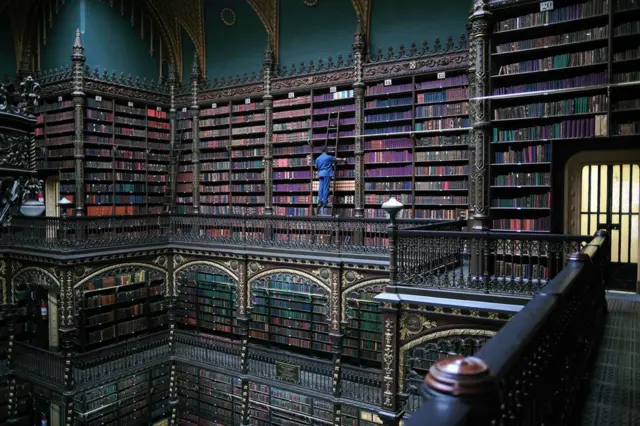 An employee selects a book from the shelves of the Royal Portuguese Cabinet of Reading in Rio de Janeiro, Brazil