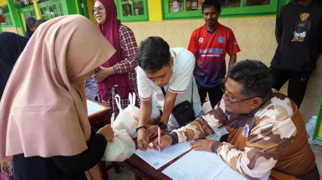 Guru membagikan paket MBG di SD Al Jihad Kota Sorong, Papua Barat Daya, Senin (22/12/2025). Sejumlah sekolah di Papua Barat Daya mulai membagikan paket MBG seminggu sekali berupa buah, roti, susu, kue kering, keripik tempe dan kue basah.