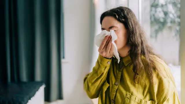 Mulher assoando o nariz