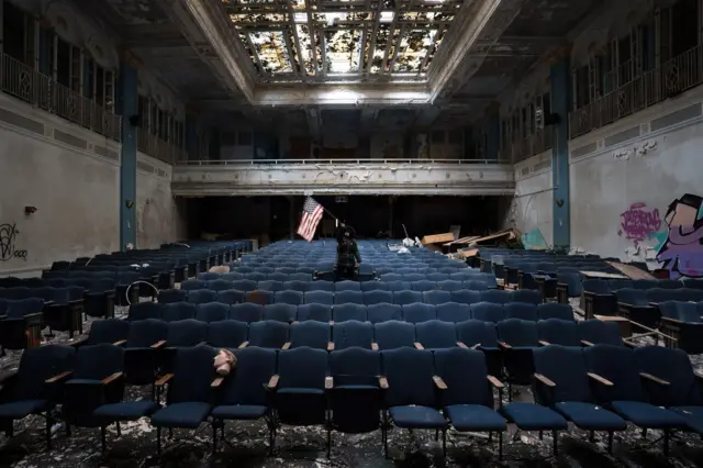 Ikumi Nakamura sostiene una bandera dentro de un auditorio abandonado